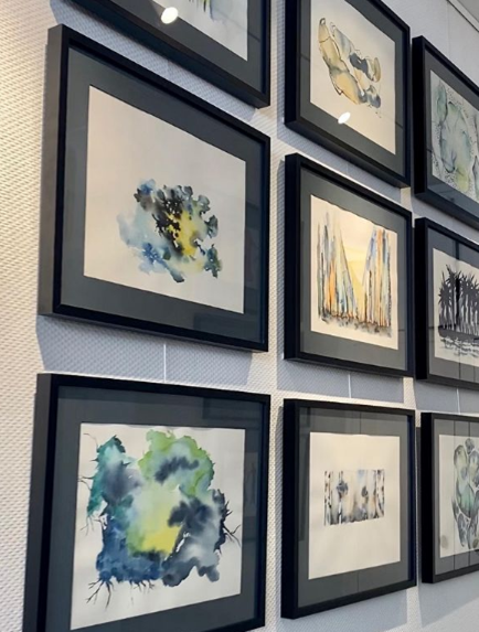 Neuf tableaux accrochés sur un mur d'exposition.